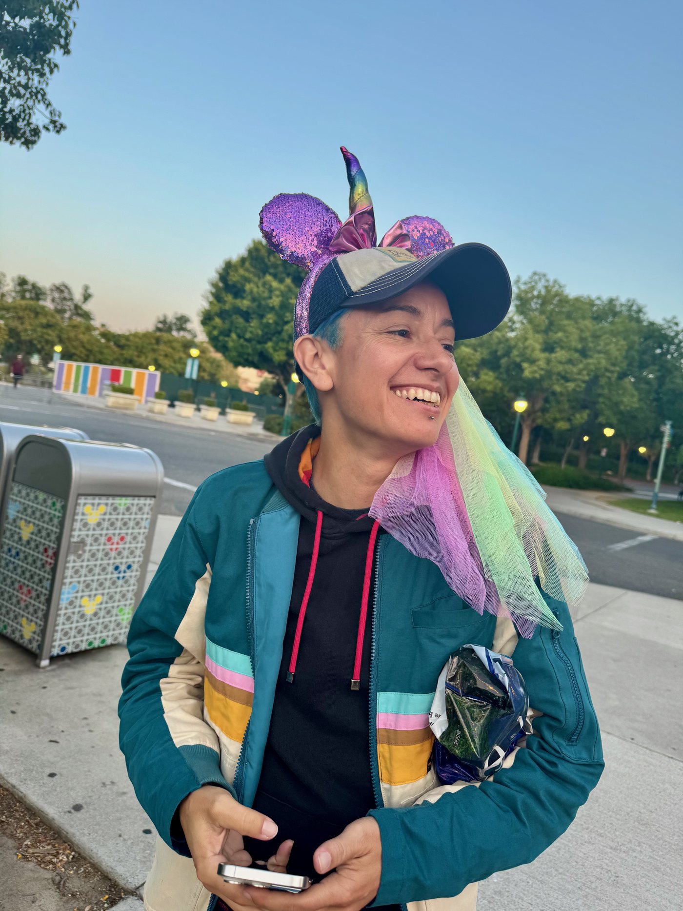 Riley smiling at Disneyland at dusk, wearing sparkly Minnie ears